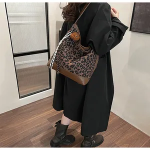 Close-up of leopard print tote bag featuring brown leather trim and a cute bear charm
