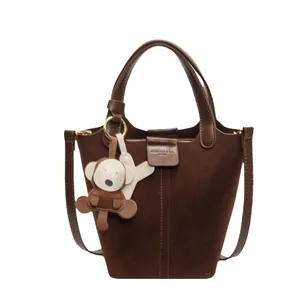 Dark brown bucket bag in suede and leather with a cute monkey charm and strap