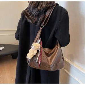 Brown retro hobo bag shown from back view with bear pendant and adjustable strap