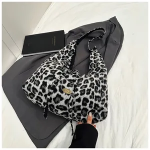 Detailed macro view of leopard print plush tote bag with a gold handmade metal tag