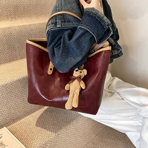 Retro large burgundy leather tote bag with grid texture and cute bear charm shown with model