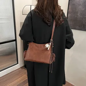 Borsa a secchiello marrone in ecopelle con portachiavi da baseball indossata a tracolla