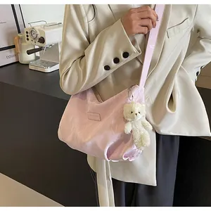 Details einer hellrosa Samt-Tragetasche mit süßem Plüschbären-Anhänger und Textur-Finish