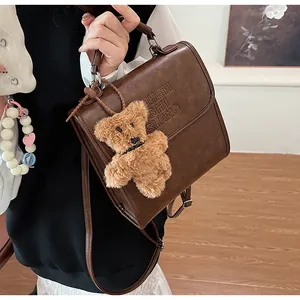 Detail of vintage brown leather backpack featuring embossed letters and bear charm