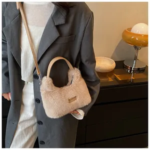 Detail of beige faux fur handbag with leather ring handle and sleek metal logo plate