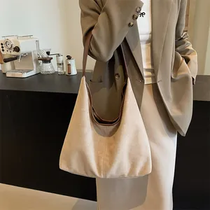 Minimalist beige matte hobo shoulder bag with dark brown leather handle in a cafe setting