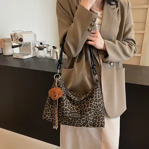 Chic leopard print tote bag with leather straps and teddy bear charm in a cafe setting