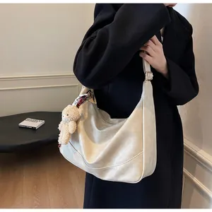 Detail of cream oversized tote bag with silk scarf knot and plush bear charm accent