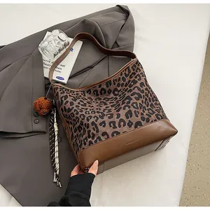 Detail of leopard print tote bag featuring brown leather base and fashion bear charm
