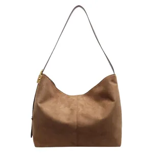 Brown suede hobo tote bag with adjustable leather strap in a minimalist retro style