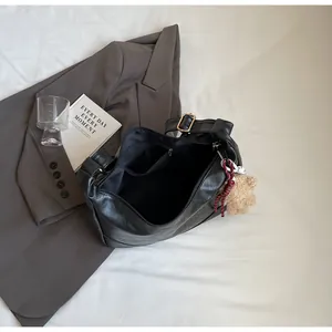 Top view of spacious black leather tote bag with soft lining and cute teddy bear charm