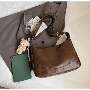 Detail of retro dark brown shoulder bag with plush bear charm and checkered scarf