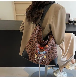 Detail of leopard print tote bag with cartoon dog graphic and black leather corners