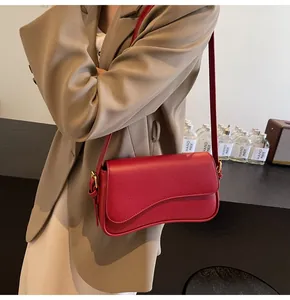 Detail of red litchi texture leather handbag with golden hardware and curved flap cover
