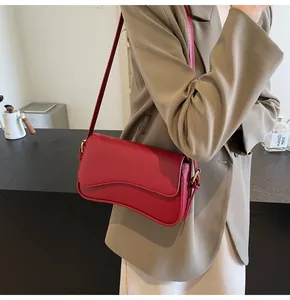 Detail of red lychee pattern leather handbag with wavy flap and gold hardware ring
