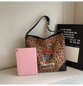 Detail of large leopard print tote bag featuring dachshund illustrations with a tablet for scale