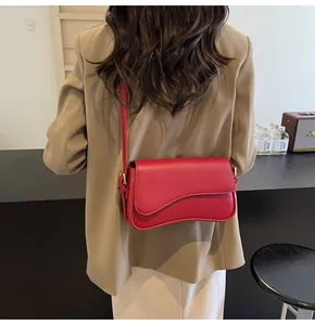 Detail of rose red lychee texture leather crossbody bag with curved flap on shoulder