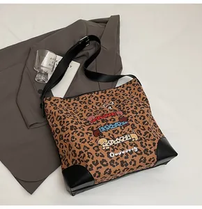 Detail of leopard print tote bag featuring colorful dachshunds and leather corners