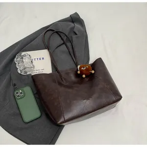 Gros plan d'un cabas marron rétro avec charme en peluche sur un veston gris