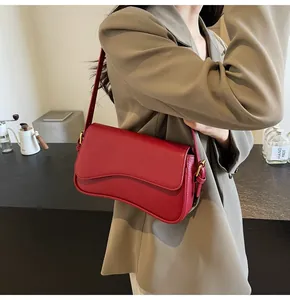 Model showcasing a red litchi texture leather underarm bag with gold metal buckle detail