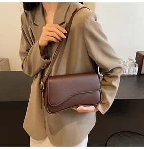 Detail of lychee pattern leather and asymmetric curved flap on brown crossbody bag