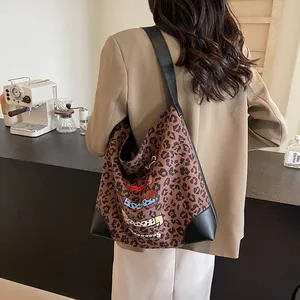 Large leopard print tote bag with cartoon design and leather straps in a cafe setting