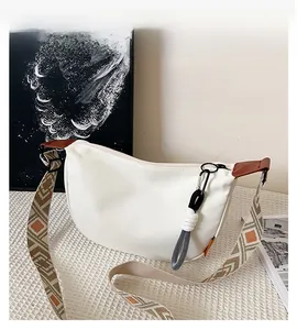 Détail du sac bandoulière blanc demi-lune avec large sangle au motif ethnique géométrique