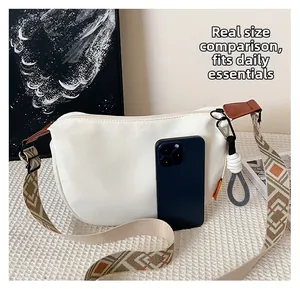 Sac bandoulière blanc en demi-lune avec smartphone pour comparaison de taille réelle