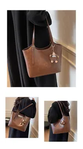 Detail of vintage brown quilted leather tote bag with monster plush pendant and metal buckle
