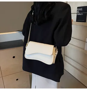 Detail of off-white lychee texture leather bag with unique wavy flap on a model