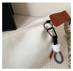 Détail de la fermeture éclair en métal et du charme tissé sur un sac en toile blanc