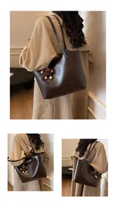Detail of dark brown tote bag with leather texture and cute plush bear charm