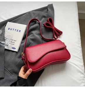 Close-up of a red litchi texture leather handbag with unique wave-shaped flap design