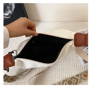 Vue détaillée du grand sac bandoulière en toile blanche avec doublure noire et sangle