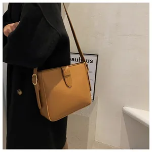 Detail einer braunen Leder-Beuteltasche mit goldenen Beschlägen und verstellbarem Gurt