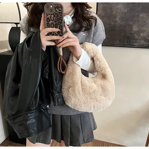 Detail of soft apricot plush crescent handbag held by a model for autumn winter style