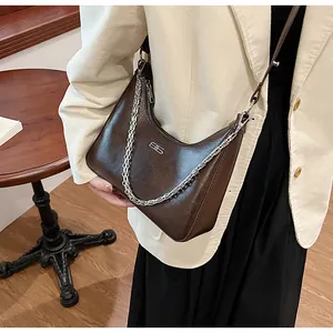 Detail of dark brown glossy leather hobo bag with silver chain and ES metal logo