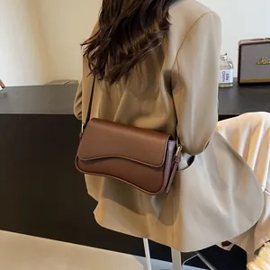 Dark brown lychee texture leather crossbody bag with wavy flap shown on model