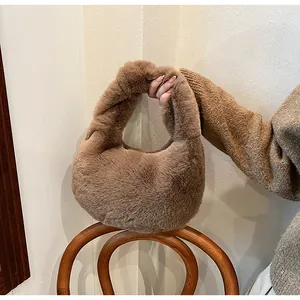 Detail of soft brown plush faux fur handbag with a crescent silhouette and wide handle