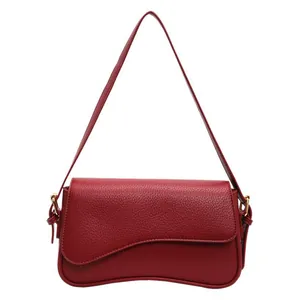 Deep red lychee grain leather crossbody bag featuring an asymmetric wavy flap design