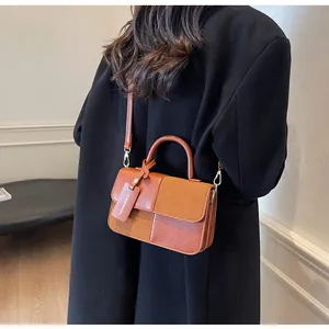 Detalle de bolso bandolera bicolor con textura de ante y etiqueta de moda en abrigo negro