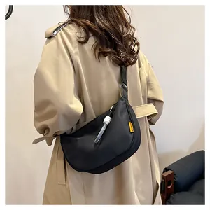 Détail du sac demi-lune noir avec étiquette jaune et tirette blanche en forme de nœud
