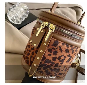 Detail of leopard print bucket bag with golden double zipper and brown leather trim