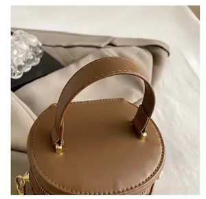 Detail of dark brown leather bucket bag handle with contrast stitching and gold D-ring hardware