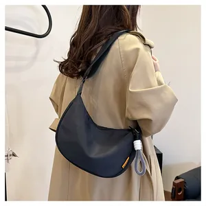 Détail du sac croissant en nylon noir avec étiquette FASHION et breloque corde