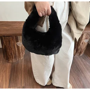 Detail of a plush black faux fur handbag held by a model in a cozy indoor setting