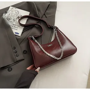 Close-up of vintage burgundy shoulder bag featuring glossy texture and silver chain strap