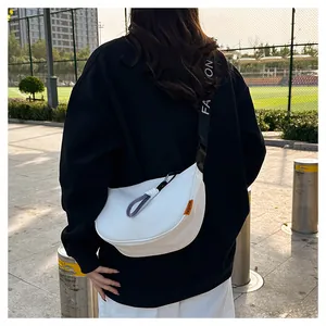 Gros plan sur le sac demi-lune blanc avec sangle FASHION et étiquette orange vive