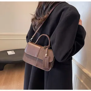 Vista trasera del bolso bandolera de cuero PU marrón y ante sobre el hombro de un modelo