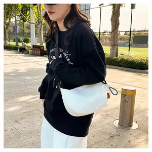 Détail du sac demi-lune blanc minimaliste avec bandoulière noire réglable et étiquette